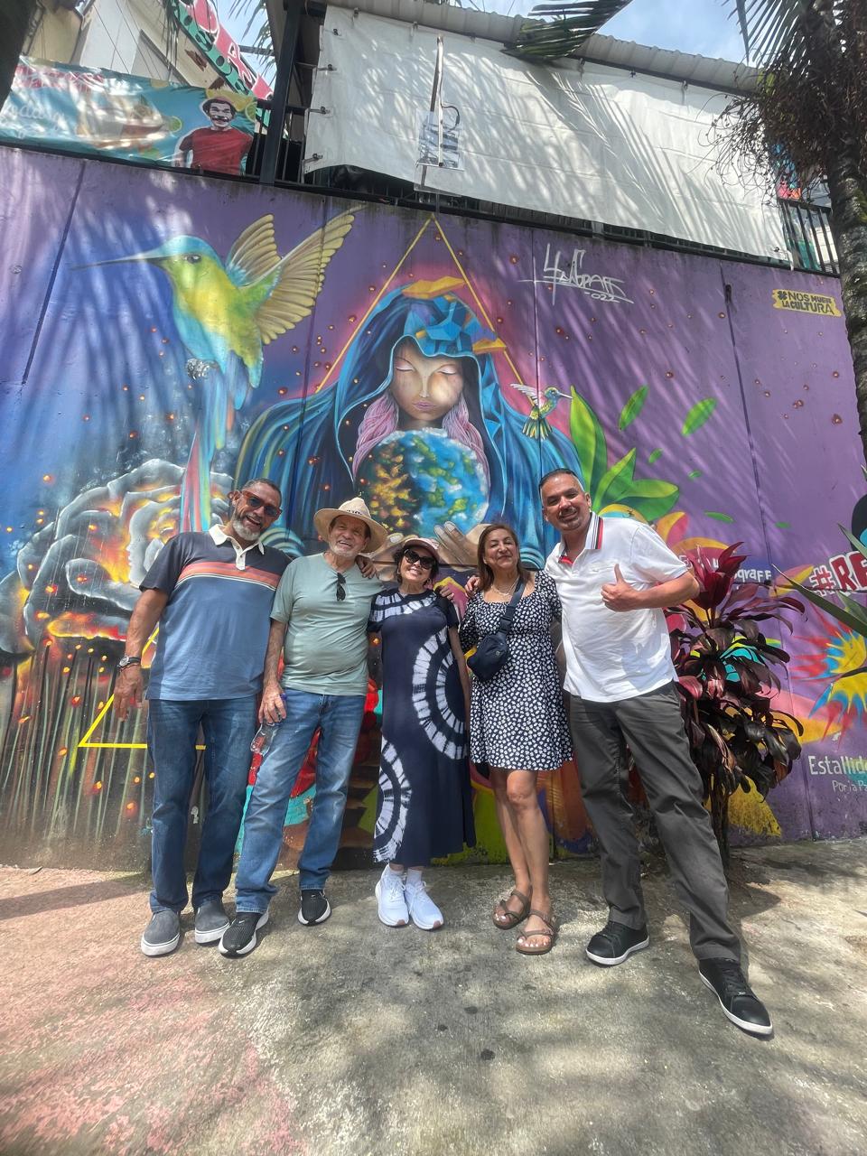 Tour group posing in front of a large Comuna 13 street-art mural