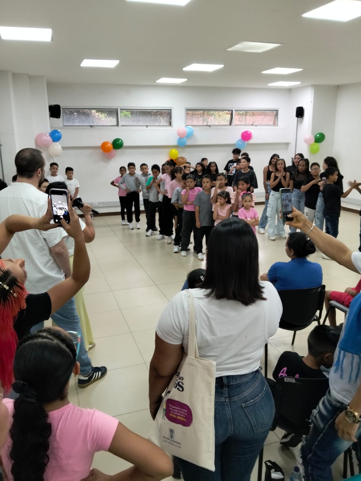 Children lined up on stage as parents film the entrepreneurship graduation