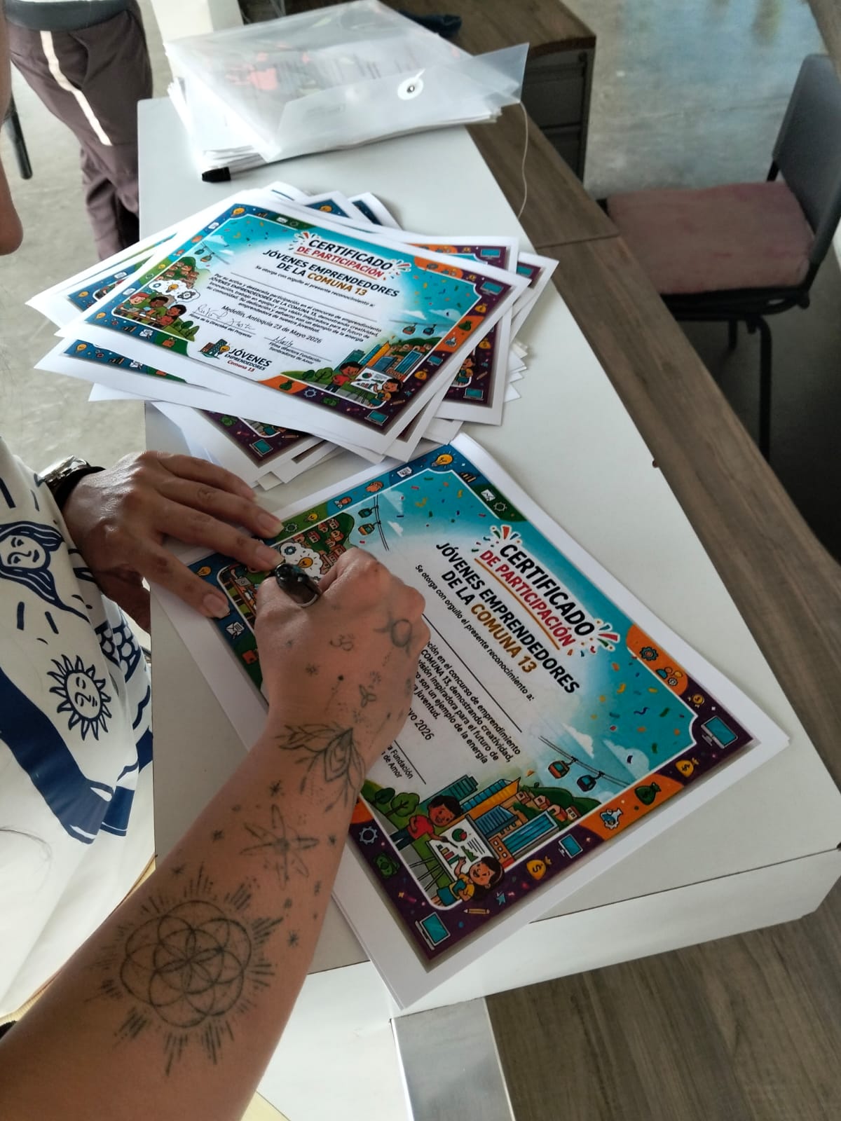 Signing participation certificates for Jóvenes Emprendedores de la Comuna 13