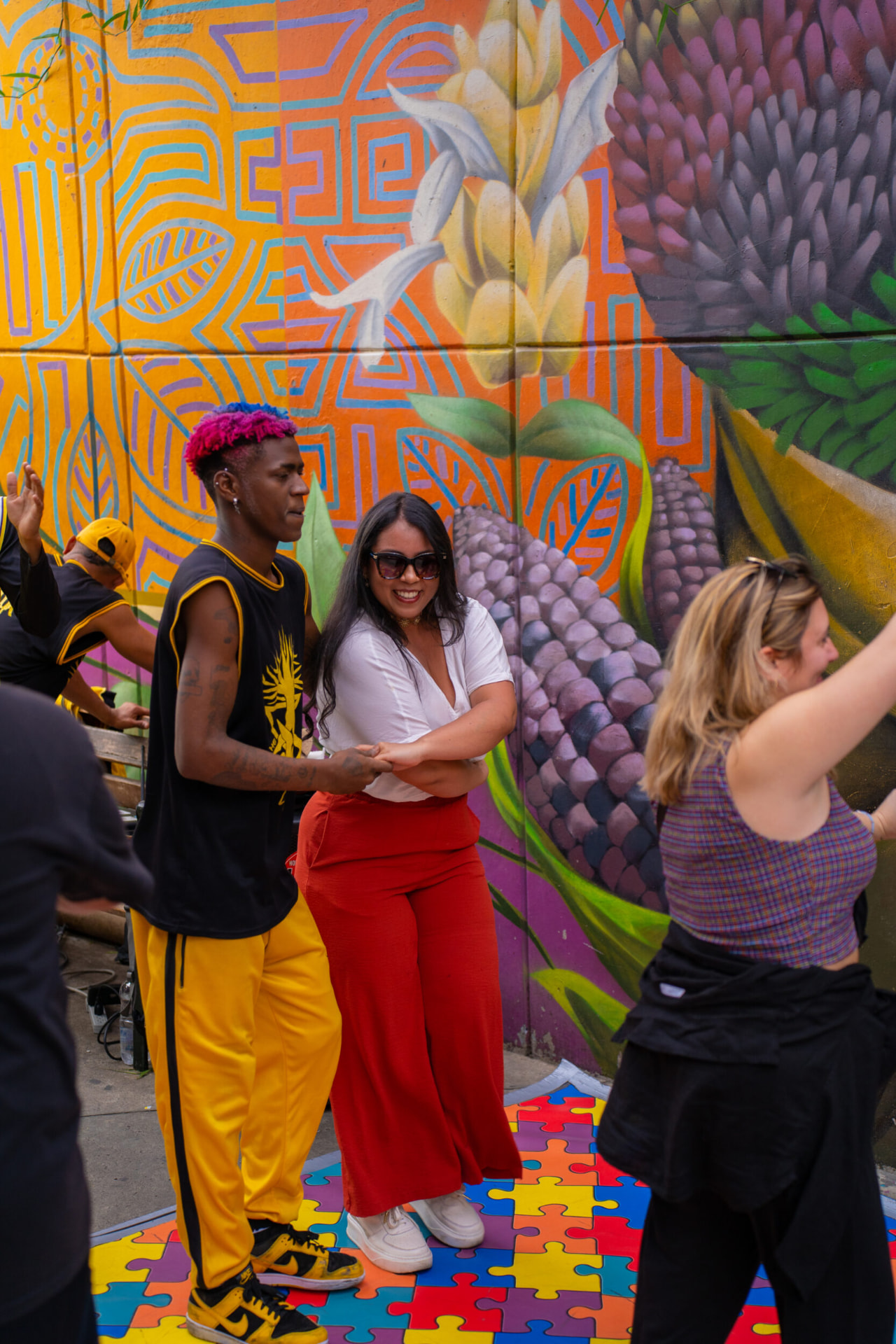 Travellers dancing with local hip-hop artists in front of a Comuna 13 mural